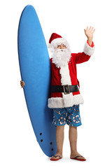 Happy santa claus on a holiday with a surfboard waving at the camera