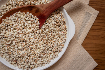 Picture of millet in a wooden spoon that is cereal and food on a brown tablecloth, wood grain, suitable for food advertising,top viwe