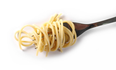 Swirls of cooked spaghetti with fork isolated on white, top view