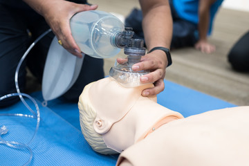 Demonstrating CPR (Cardiopulmonary resuscitation) training medical procedure on CPR doll in the class.Paramedic demonstrate first aid practice for save life.Doctor holding breathing bag(Ambu bag).