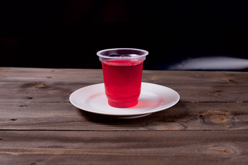 Berry jelly in a plastic Cup in a white plate on a wooden background