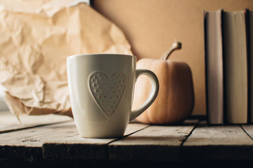 Pumpkin, tea and autumn leaves on the background. Autumn still life with pumpkin, candle and cup of tea on the wooden table. Thanksgiving, autumn season. Copy spase