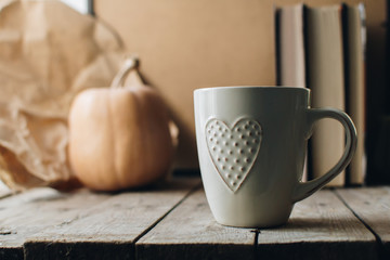 Pumpkin, tea and autumn leaves on the background. Autumn still life with pumpkin, candle and cup of tea on the wooden table. Thanksgiving, autumn season. Copy spase