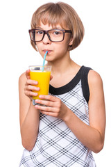Beautiful caucasian little girl drinking fresh orange juice. Emotional portrait of attractive happy child with eyeglasses, isolated on white background.