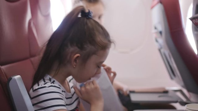 Little girl on the plane vomited in a paper bag. A Little girl feels bad in the cockpit. The fear of flying.
