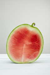 ripe red delicious watermelon half on wooden white table isolated on grey