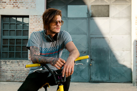 Underground subculture, cool punker tattooed man on bike, with headphones 