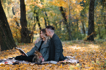 Beautiful young couple resting in autumn park. autumn concept. Loving couple resting with their cat.