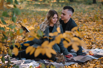 Young loving couple rests in autumn park, man embraces a woman.