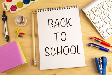 School supplies on wooden background. Back to school concept with text in the notepad.