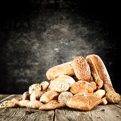 Rolls and braed on wooden table top and black wall.