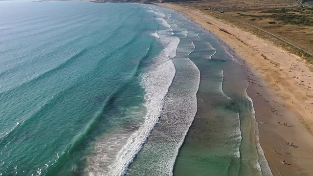 ocean waves sandy beach with people bathing in the water view from drone Lanzada beach Galicia Spain 4k video