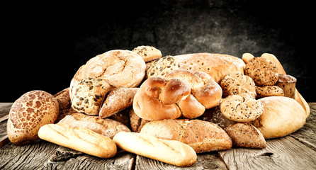Rolls and braed on wooden table top and black wall.