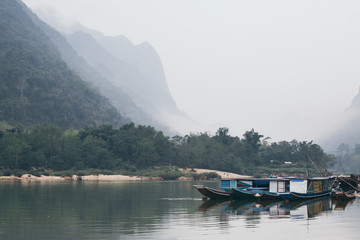 Fototapeta na wymiar Traditional Laotian wooden slow boat on Nam Ou river near Nong Khiaw village, Laos