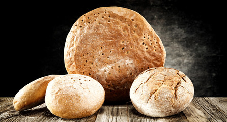 Rolls and braed on wooden table top and black wall.