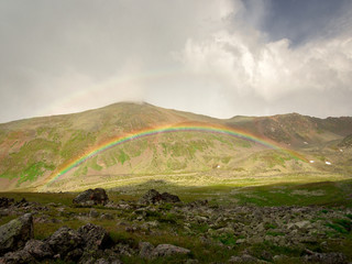 Summer background of green mountain slopes with a rainbow, Teberda, Karachay-Cherkessia, Russia