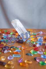 Quartz crystal on a wooden surface with multicolored glass cabochons