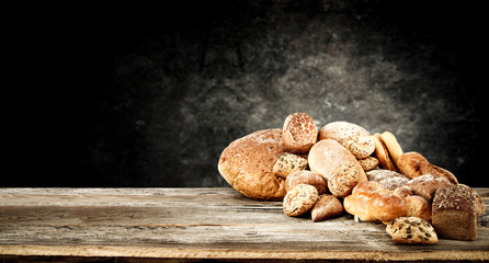 Rolls and braed on wooden table top and black wall.
