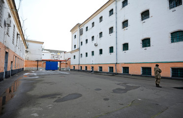 Prison yard, windows, bars of the detention facility and guard standing