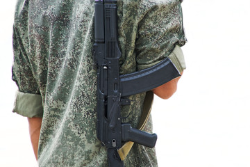 A boy with a gun in protective clothing khaki on a white background. Back. Patrol or security....