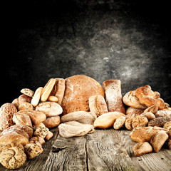 Rolls and braed on wooden table top and black wall.