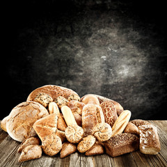 Rolls and braed on wooden table top and black wall.