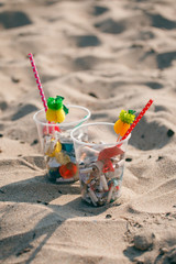 Cocktail with garbage and tropical decor on clean beach. Plastic ocean pollution, environmental crisis. Say no plastic. Single-use plastic waste, world ocean day