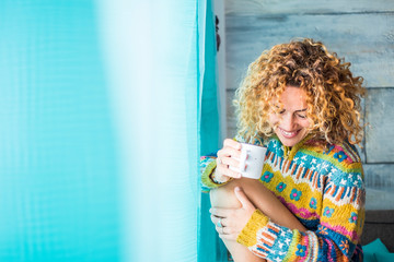 Beautiful adult caucasian woman relax at home wit cup of tea or coffee - blonde long curly hair and...
