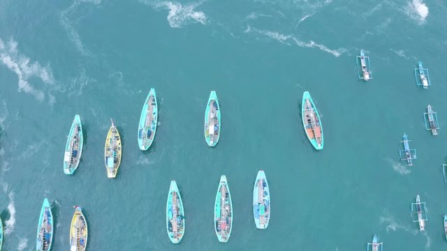 Top down view of wooden traditional fisherman boats anchoring on the Papuma Beach in Jember, East Java, Indonesia. Shot in 4k resolution from a drone flying upwards