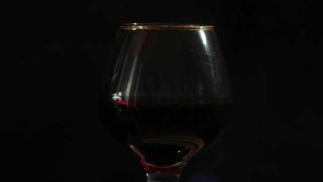 A glass of red wine on fire stands on a beautiful natural stone