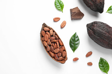 Cocoa pods with beans and chocolate pieces on white background, top view