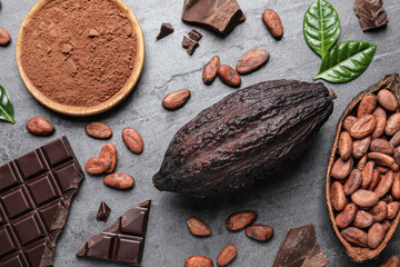 Flat lay composition with cocoa pods and chocolate on grey table