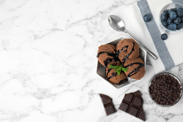 Flat lay composition with bowl of chocolate ice cream served on marble table, space for text