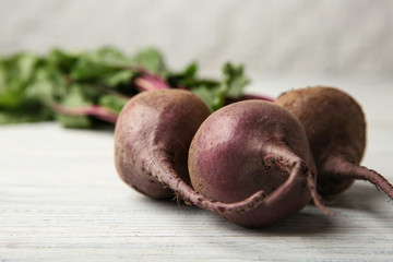 Bunch of fresh beets with leaves on wooden table against white background, closeup. Space for text