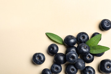 Fresh acai berries with leaves on beige background, flat lay. Space for text