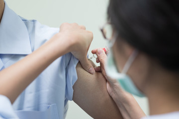 Close up doctor's hand injecting for vaccine in the shoulder man patient.Nurse using syringe are vaccination to patient for influenza protection.Medication treatment concept.
