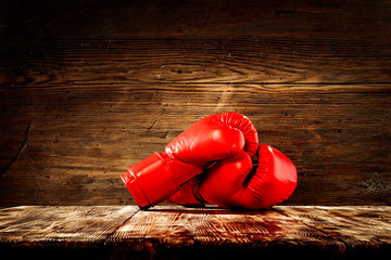 Red boxing gloves on wooden top background.