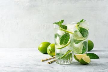 Fresh mojito cocktail with lime and mint in glass on concrete background. Cold refreshing drink. Selective focus. - obrazy, fototapety, plakaty