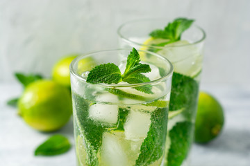 Fresh mojito cocktail with lime and mint in glass on concrete background. Cold refreshing drink. Selective focus.
