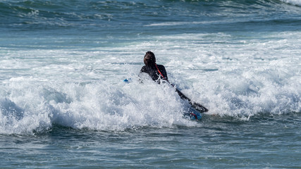 Female Surfer swimming out through the waves