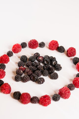 The composition of fragrant and delicious black and red raspberries on a white background are isolated in the studio.