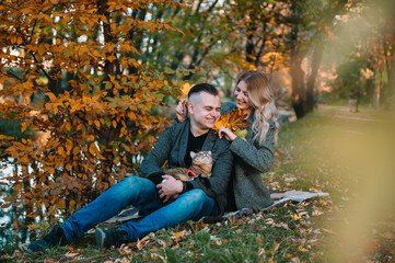 Beautiful young couple resting in autumn park. autumn concept. Loving couple resting with their cat.