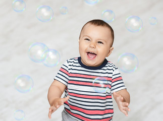 Adorable baby enjoying lots of colorful soap bubbles