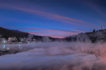 Lake view morning of the mist rising up from the water around with the hill, mountain and blue sky background, sunrise at Ban Rak Thai, Mae Hong Son, northern of Thailand.