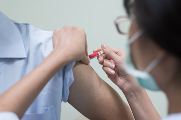 Close up doctor's hand injecting for vaccine in the shoulder man patient.Nurse using syringe are vaccination to patient for influenza protection.Medication treatment concept.