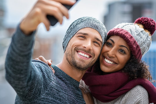 Smiling multiethnic couple taking selfie in winter