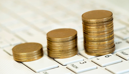 Online business success, money coins stacks on a computer keyboard