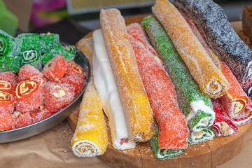 Eastern sweetness in Turkish pleases with multi-colored rolls and tubes with nuts and coconut. Closeup of Turkish sweets on the market, selective focus.