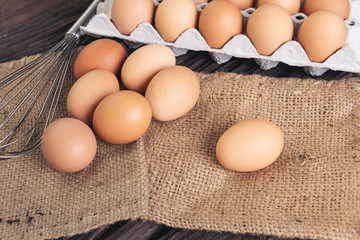  raw chicken eggs on sack cloth fabric on old brown wooden