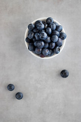 Fresh blueberries in a white bowl on a gray background. Top view.